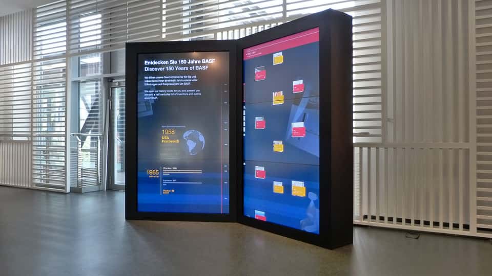 Multi-screen “open book” media installation at the BASF Visitor Center, visualizing over a century of BASF history through a synchronized, touch-enabled digital timeline across large-format displays.
