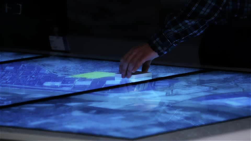 Moderator using a physical marker on the multitouch surface to control and highlight site information.